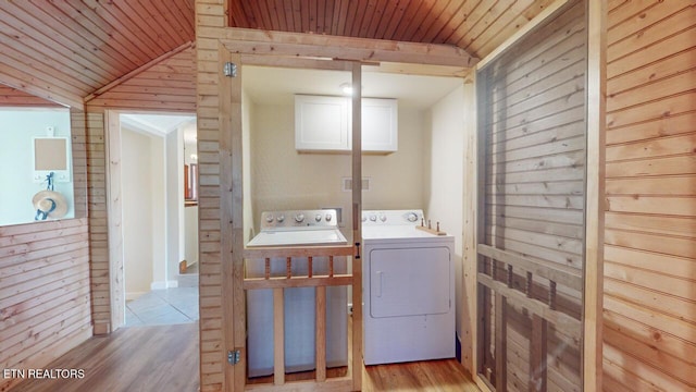 laundry area with washing machine and clothes dryer, sink, wooden ceiling, wooden walls, and light hardwood / wood-style floors