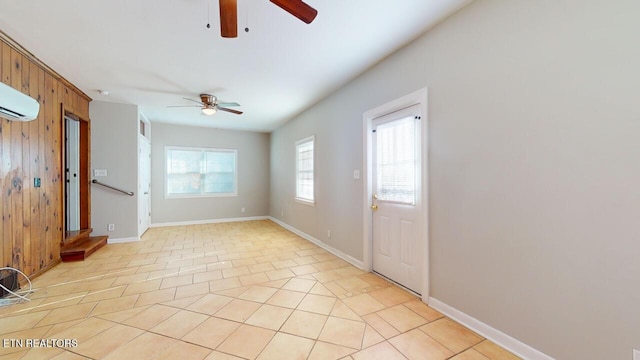 tiled foyer featuring a wall mounted AC, ceiling fan, and wood walls