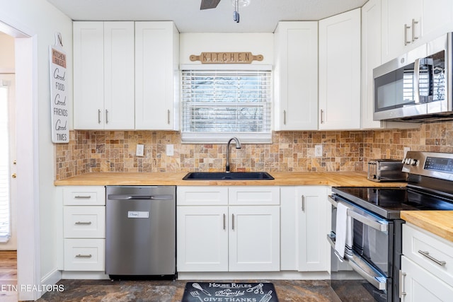 kitchen with stainless steel appliances, wooden counters, and white cabinets