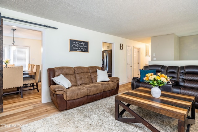 living room with wood-type flooring, a barn door, and a textured ceiling