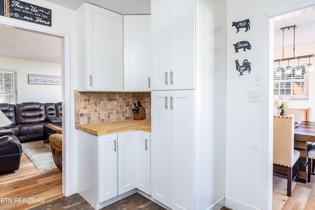 kitchen with backsplash, wood-type flooring, butcher block countertops, and white cabinets