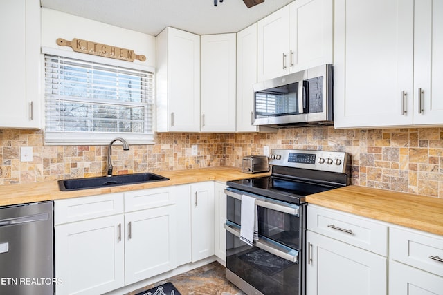 kitchen featuring sink, appliances with stainless steel finishes, white cabinetry, tasteful backsplash, and wood counters