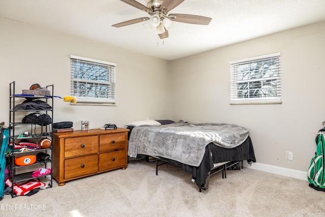 bedroom featuring ceiling fan, light colored carpet, multiple windows, and a textured ceiling