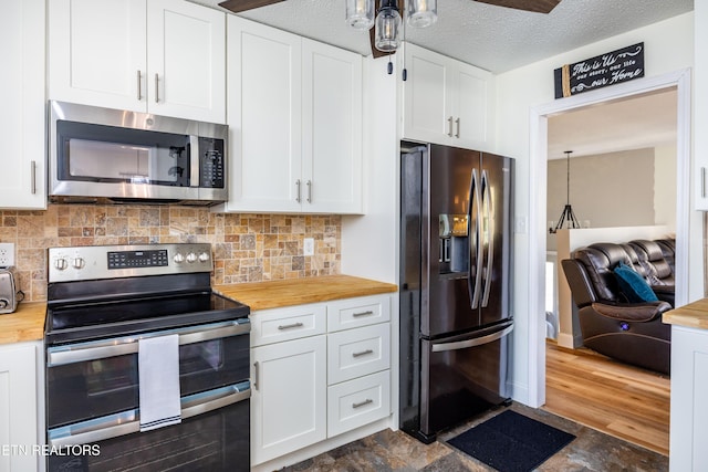 kitchen featuring stainless steel appliances, white cabinetry, pendant lighting, and wooden counters