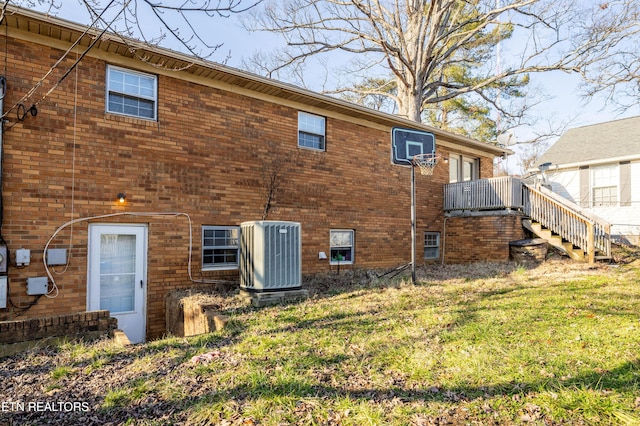 rear view of house with central AC and a lawn