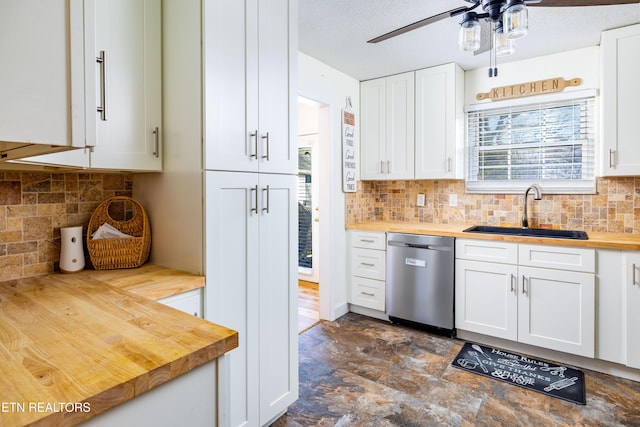 kitchen featuring butcher block counters, sink, white cabinetry, stainless steel dishwasher, and backsplash