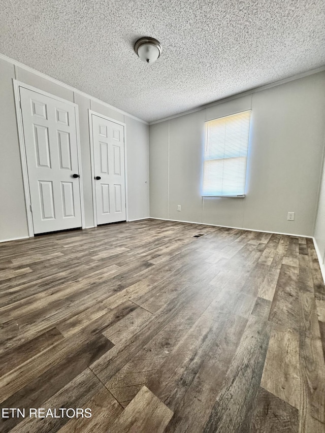 unfurnished bedroom featuring wood-type flooring, ornamental molding, a textured ceiling, and a closet