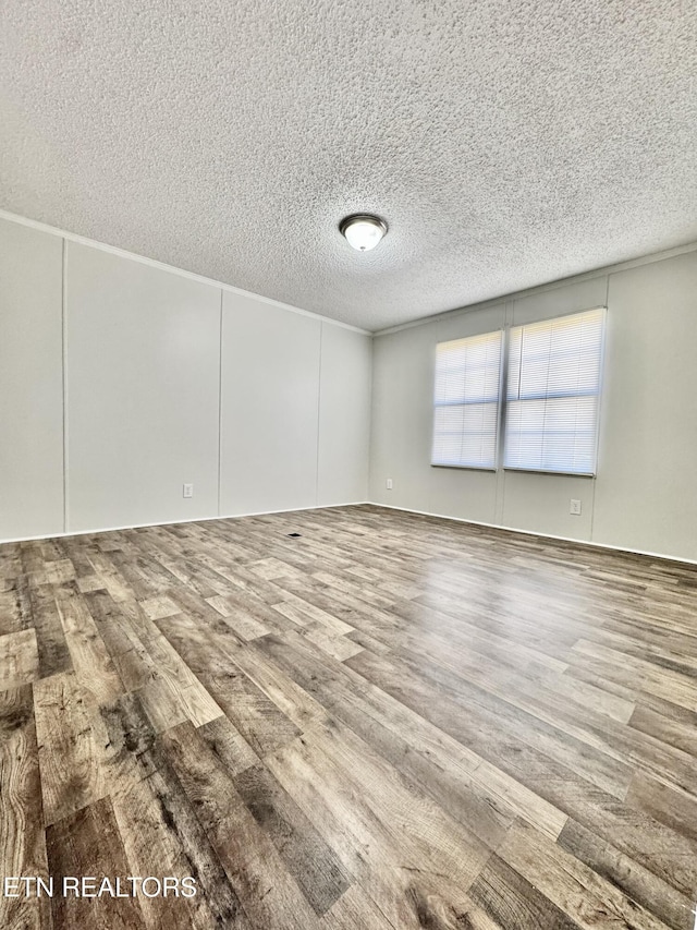 spare room featuring hardwood / wood-style flooring and a textured ceiling