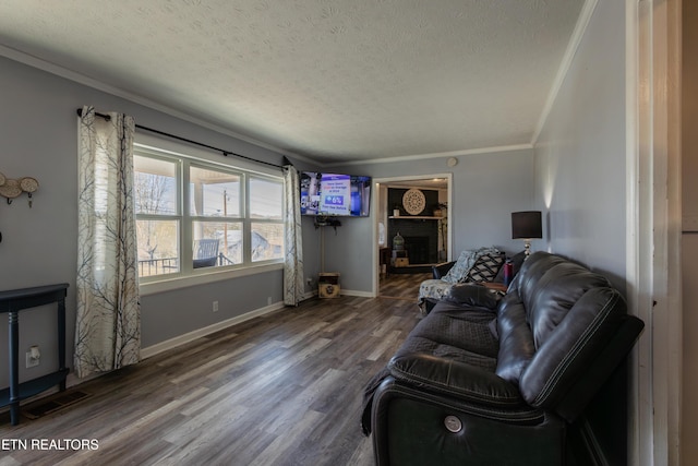 living room with crown molding, wood-type flooring, a brick fireplace, and a textured ceiling