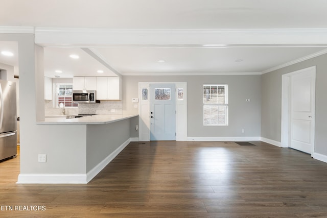 kitchen with appliances with stainless steel finishes, hardwood / wood-style floors, white cabinetry, kitchen peninsula, and crown molding