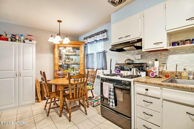 kitchen featuring sink, backsplash, range with gas stovetop, white cabinets, and decorative light fixtures