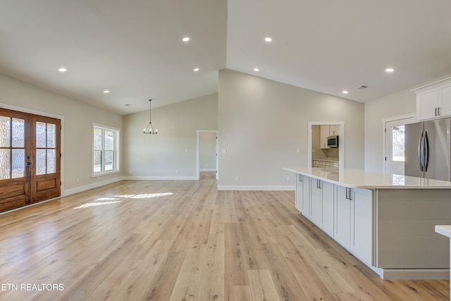 kitchen featuring stainless steel refrigerator, decorative light fixtures, white cabinetry, a spacious island, and light hardwood / wood-style flooring