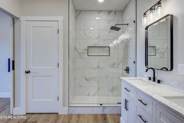 bathroom featuring wood-type flooring, vanity, and a tile shower