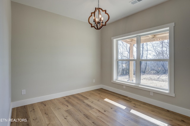 empty room with an inviting chandelier and light hardwood / wood-style floors