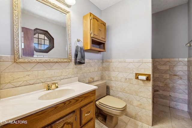 bathroom featuring vanity, toilet, tile patterned flooring, and tile walls