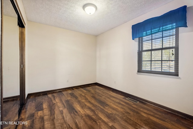 unfurnished room with dark hardwood / wood-style floors and a textured ceiling