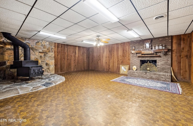 interior space with a wood stove, a fireplace, and wood walls