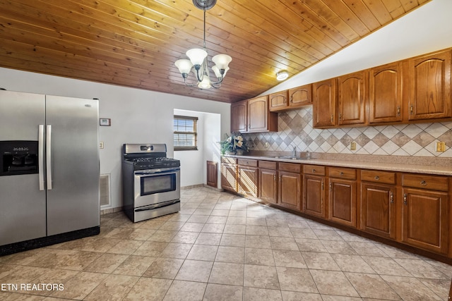 kitchen with sink, light tile patterned floors, appliances with stainless steel finishes, hanging light fixtures, and backsplash