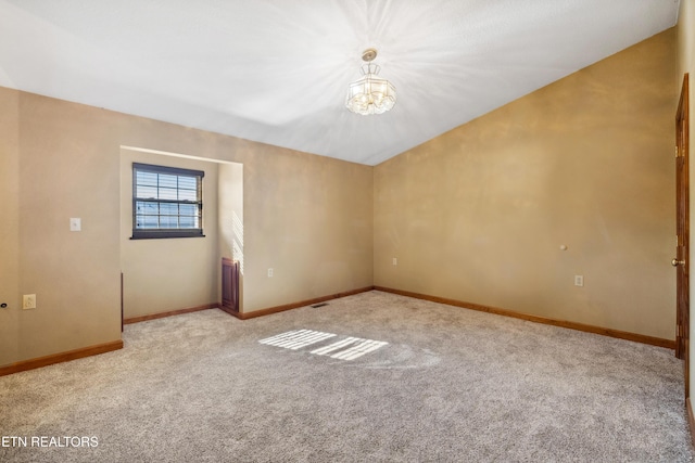 spare room featuring light carpet and an inviting chandelier