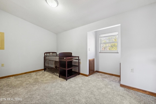 bedroom with vaulted ceiling, light colored carpet, and a textured ceiling