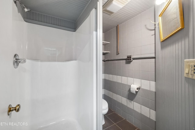 bathroom with tile patterned floors, toilet, tile walls, and a shower