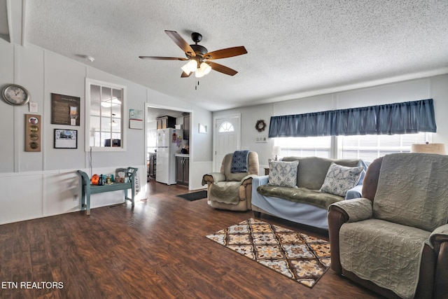 living room featuring lofted ceiling, ceiling fan, dark wood-type flooring, and a textured ceiling