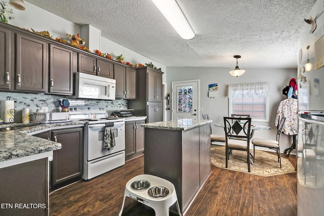 kitchen featuring dark brown cabinetry, dark stone countertops, dark hardwood / wood-style flooring, pendant lighting, and white appliances