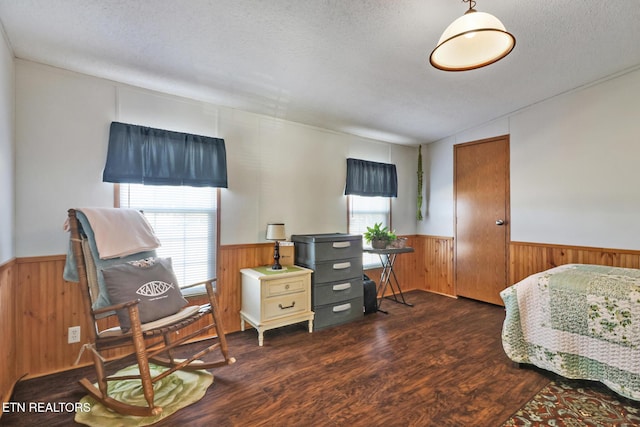 bedroom featuring multiple windows, dark hardwood / wood-style flooring, a textured ceiling, and wood walls