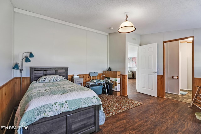 bedroom with dark wood-type flooring, a textured ceiling, and wood walls