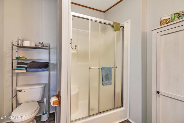 bathroom featuring a shower with door, ornamental molding, and toilet