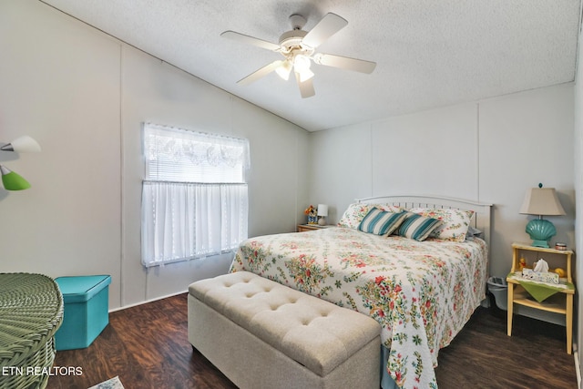 bedroom with vaulted ceiling, dark wood-type flooring, ceiling fan, and a textured ceiling