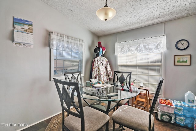 dining area with a textured ceiling and dark hardwood / wood-style flooring