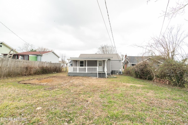 rear view of property featuring central AC, covered porch, and a lawn