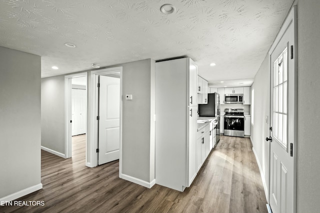 kitchen with white cabinetry, appliances with stainless steel finishes, a textured ceiling, and hardwood / wood-style flooring