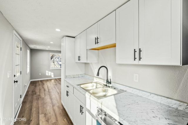 kitchen with sink, light stone counters, a textured ceiling, white cabinets, and dark hardwood / wood-style flooring