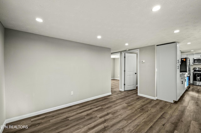 basement with stainless steel fridge, a textured ceiling, and dark hardwood / wood-style flooring