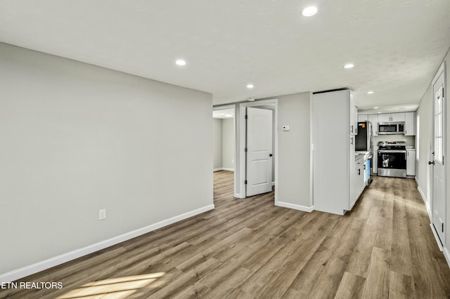 interior space with white cabinetry, appliances with stainless steel finishes, a textured ceiling, and light wood-type flooring