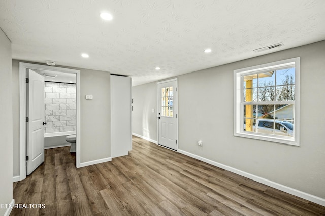 unfurnished bedroom featuring dark hardwood / wood-style flooring, connected bathroom, and a textured ceiling