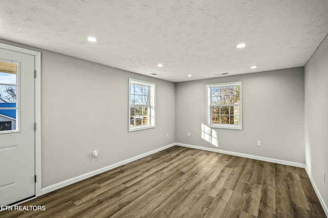 unfurnished room featuring plenty of natural light, hardwood / wood-style floors, and a textured ceiling