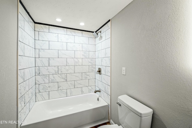 bathroom featuring tiled shower / bath combo, a textured ceiling, and toilet