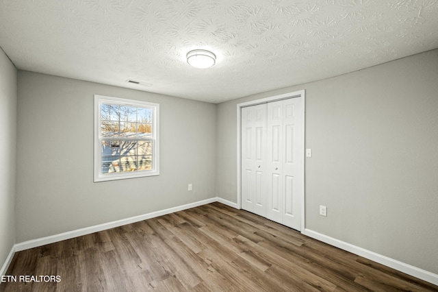 unfurnished bedroom with hardwood / wood-style flooring, a closet, and a textured ceiling