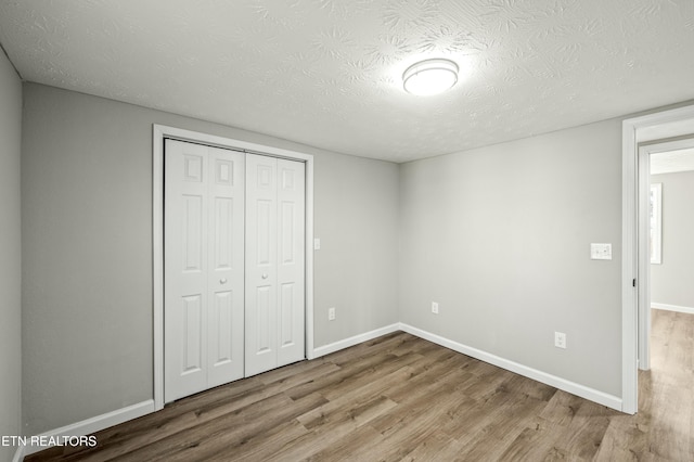 unfurnished bedroom featuring light hardwood / wood-style flooring, a closet, and a textured ceiling