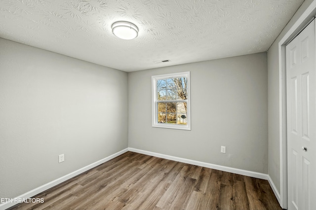 unfurnished bedroom with hardwood / wood-style floors, a textured ceiling, and a closet