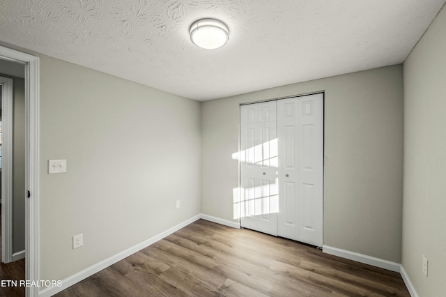 unfurnished bedroom with hardwood / wood-style flooring, a closet, and a textured ceiling