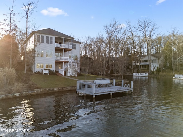 dock area featuring a water view, a balcony, and a yard