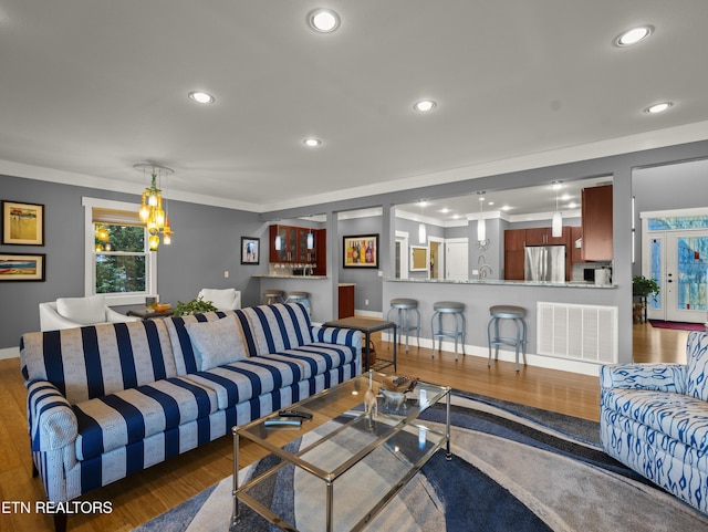 living room featuring ornamental molding, dark wood-type flooring, and an inviting chandelier