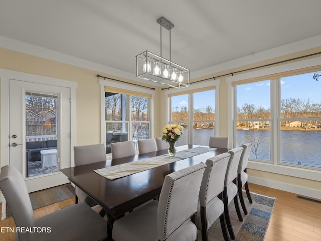 dining space with an inviting chandelier, light hardwood / wood-style flooring, and a water view