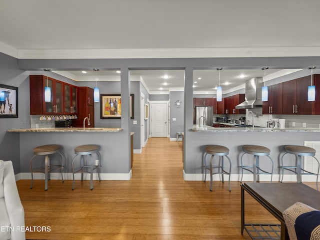 kitchen featuring ventilation hood, decorative light fixtures, stainless steel appliances, and kitchen peninsula