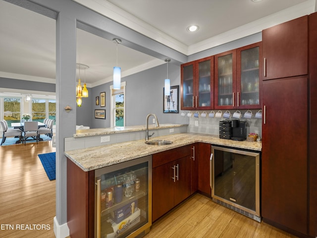 kitchen with light stone counters, sink, beverage cooler, and kitchen peninsula