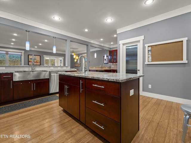 kitchen with pendant lighting, sink, stainless steel dishwasher, light wood-type flooring, and a spacious island